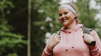 Woman smiling while she is on a hike outdoors.