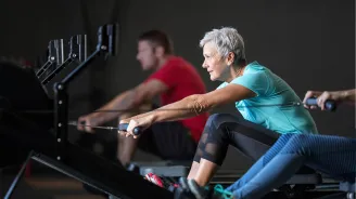 An elderly woman on a row machine.