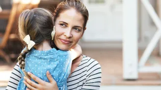 A mother hugs and comforts her daughter.