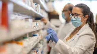 Female Pharmacist getting medication from shelf