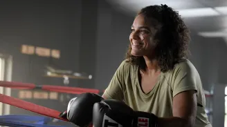 Bariatrics patient Sharlene smiling while wearing boxing gloves and standing in a boxing ring.