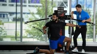 A man works with his personal trainer to do a chest fly exercise.