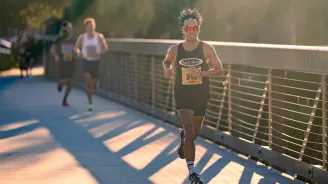 Young man running across a bridge.