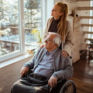 Caregiver Looks Out the Window with a Senior Patient at the Newly Fallen Snow.