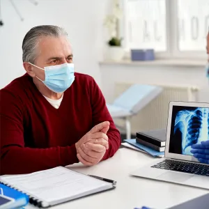A doctor showing a mature patient his x-ray results on a laptop