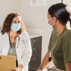 A Doctor Speaks to a Female Military Patient in an Exam Room.