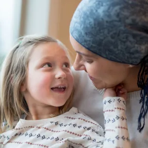 A Small Child Smiles and Touches Her Mother's Face While Sitting in a Window.