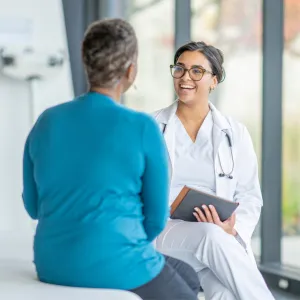 A Smiling Physician Speaks to a Patient in an Exam Room