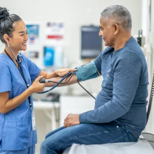 A Nurse Smiles as she Takes a Patient's Blood Pressure Readings.