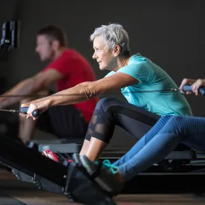 An elderly woman on a row machine.