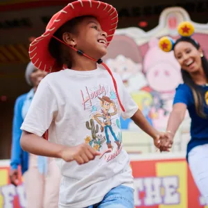 A mother holding her child's hand at a theme park.