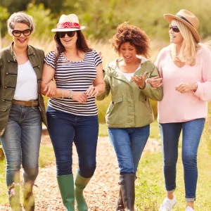 A Group of Inspiring Women Walk Through a Garden Smiling and Laughing