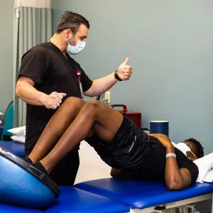 A patient doing a rehab exercise while being guided by the doctor
