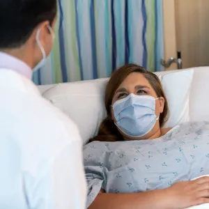 A doctor meeting with his patient while she lays in bed.