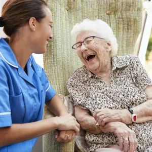 A senior woman laughs with her caregiver.