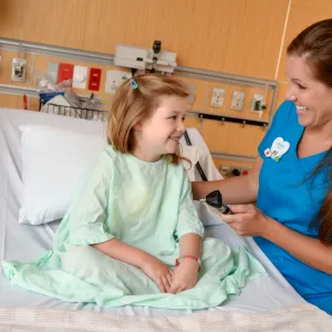 A girl smiles with her nurse