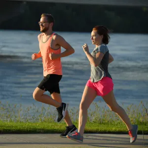 A young couple taking a morning run around a lake.