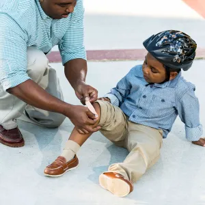 A father puts a bandage on his son's knee.