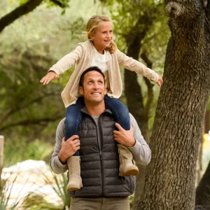 A girl sits on her dad's shoulders