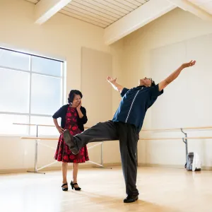 Friends are dancing while putting their arms in the air at a dance studio.