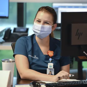 An AdventHealth employee working at a computer.
