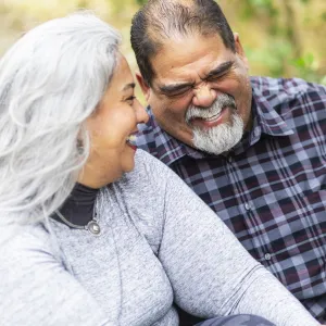 A couple laughs while on an outdoor picnic.