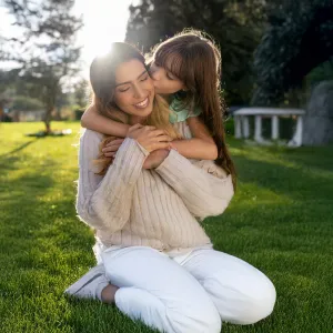 Mother and daughter embracing in yard