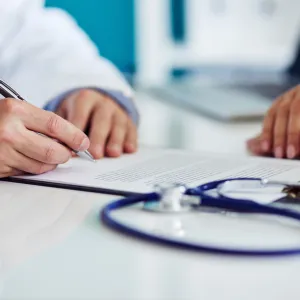 A doctor takes notes during a patient appointment.