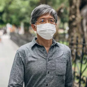 A man walking outdoors wearing a face mask.