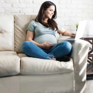 An expectant mother has a video call on her computer.