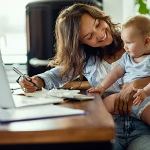 A mother and infant son at home in front of the computer.