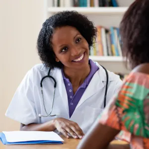 A smiling doctor talking with a female patient.