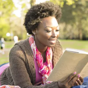 A woman reading a book outdoors.