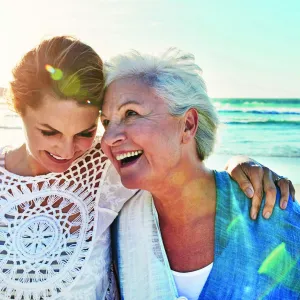 Mother and adult daughter walking on the beach together