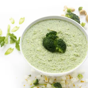 Bowl of broccoli cream soup with onion and parsley garnish