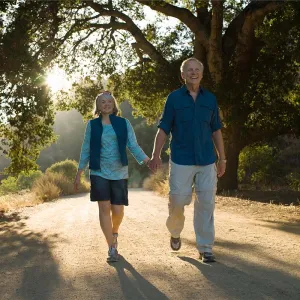 Older couple walking on a dirt road by trees