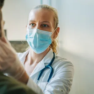 Masked physician examining patient.