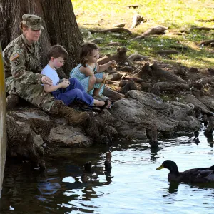 Military mom in uniform sitting with her kids in the park