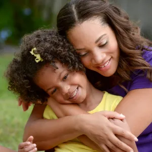 A mother hugs her daughter from behind. 