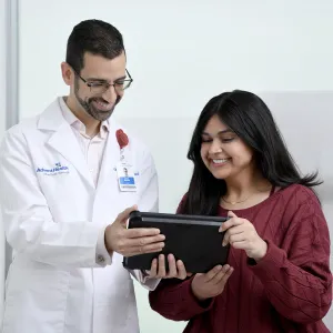 A Young woman looks at a tablet with a physician.