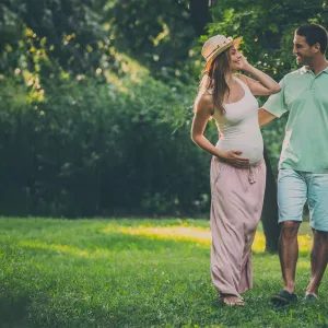 A pregnant woman walking outdoors with her husband.