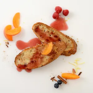 two slices of whole-grain french bread french toast, topped with a fruit sauce