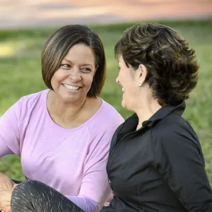 Two smiling women sitting outdoors talking
