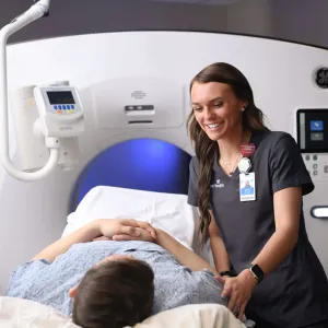 Female imaging technician preparing a male patient for a CT scan.