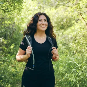 A woman on a hike while wearing a Camelbak backpack.