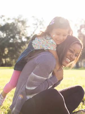 Daughter climbing on mom outdoors