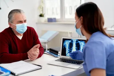 A doctor showing a mature patient his x-ray results on a laptop