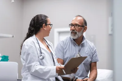 A middle-aged man talking to a female doctor.
