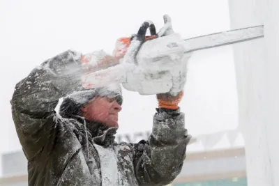 A man using a chainsaw to cut ice.