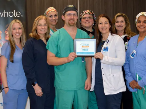 A mixed group of eight doctors and nurses in their scrubs holding an award.
